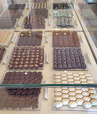 Fancy chocolates fill glass cases in the upscale chocolatier’s boutique.